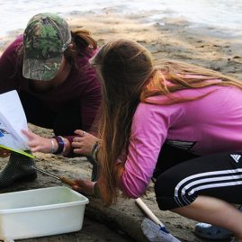 Two students conducting outdoor research at a river bank