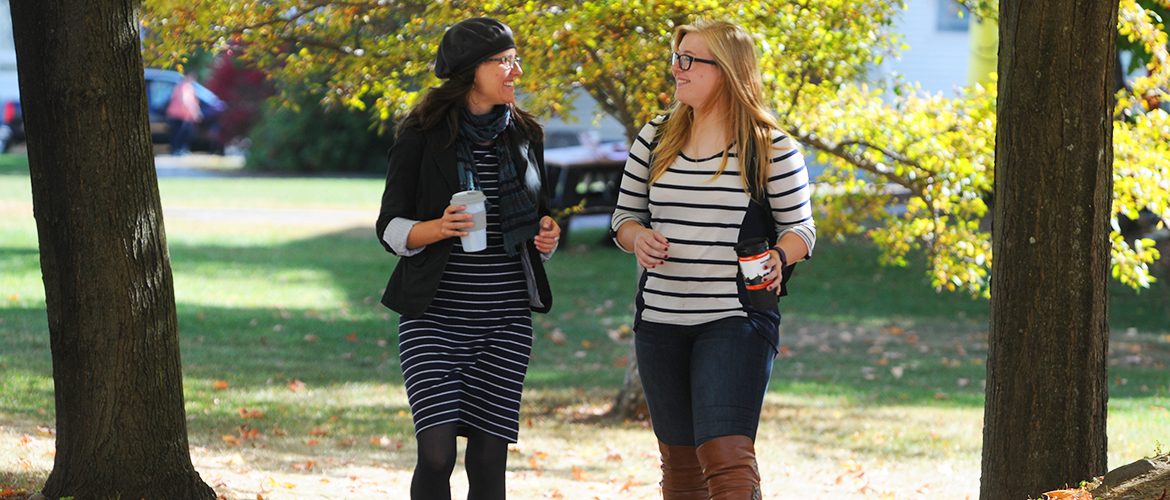 Professor and student walking outdoors on campus