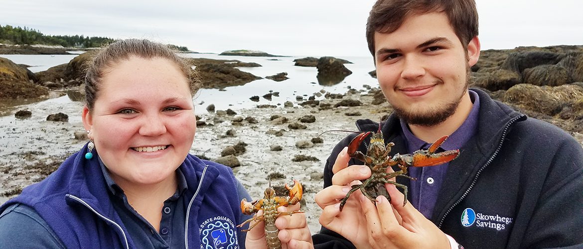 Two students holding crustaceans at the ocean