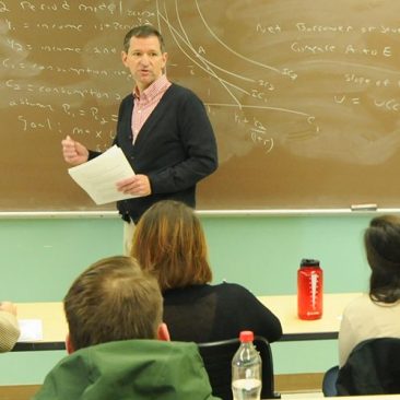 Male professor teaching classroom of students taking notes