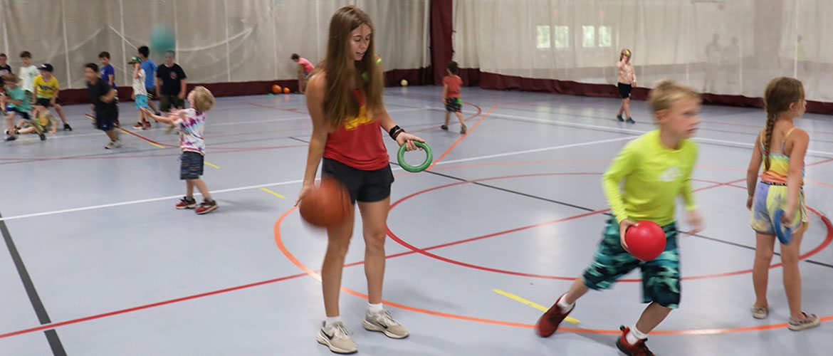 Student working with children in a phys ed class