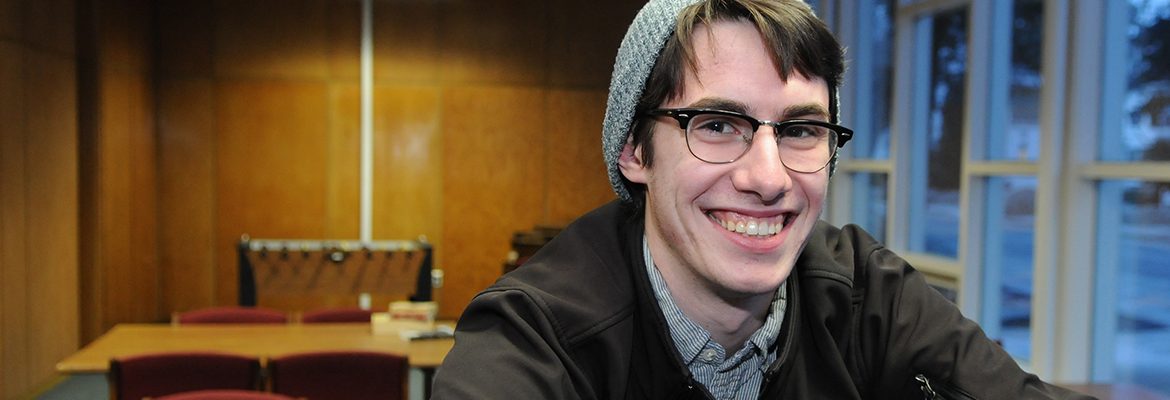 Male student with glasses smiling in student lounge