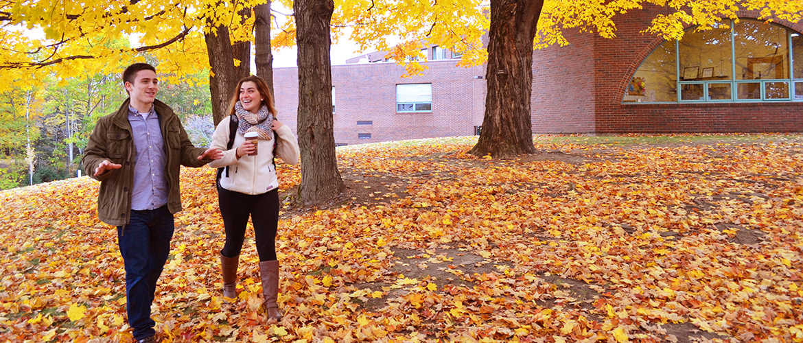 Two students walking in leaves on campus