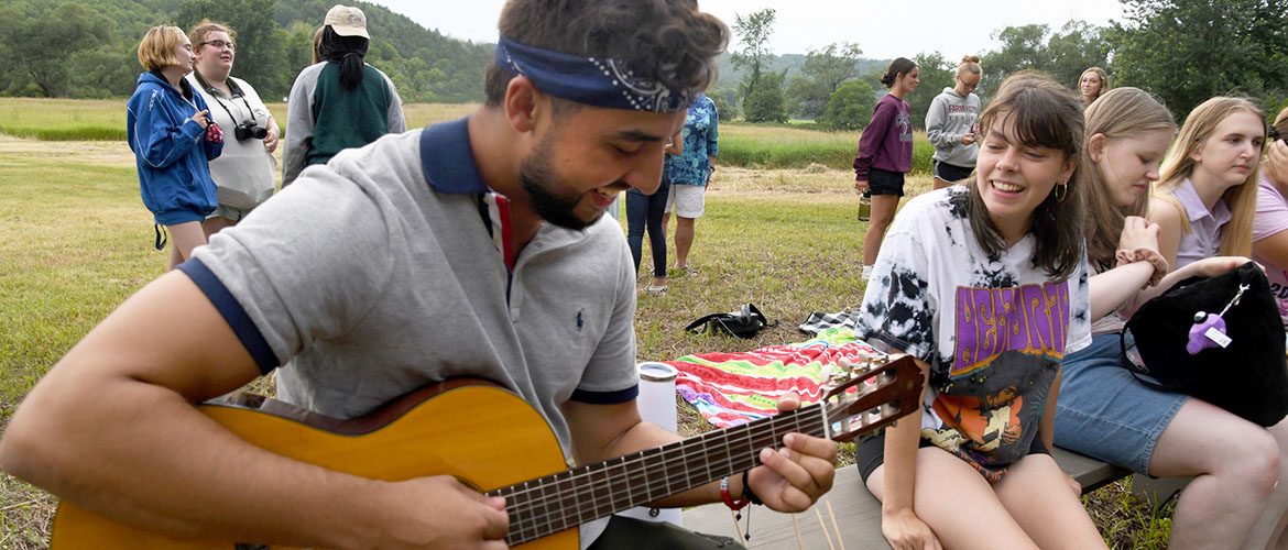 UMF student playing a guitar outdoors