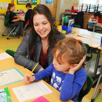 Student teacher working with a child in a school classroom