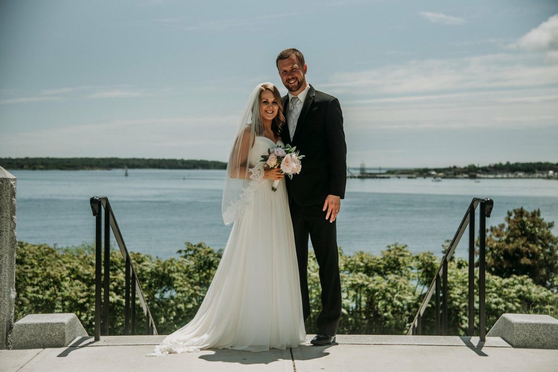 Asia and Shane in their wedding best stand at Fort Allen Park.