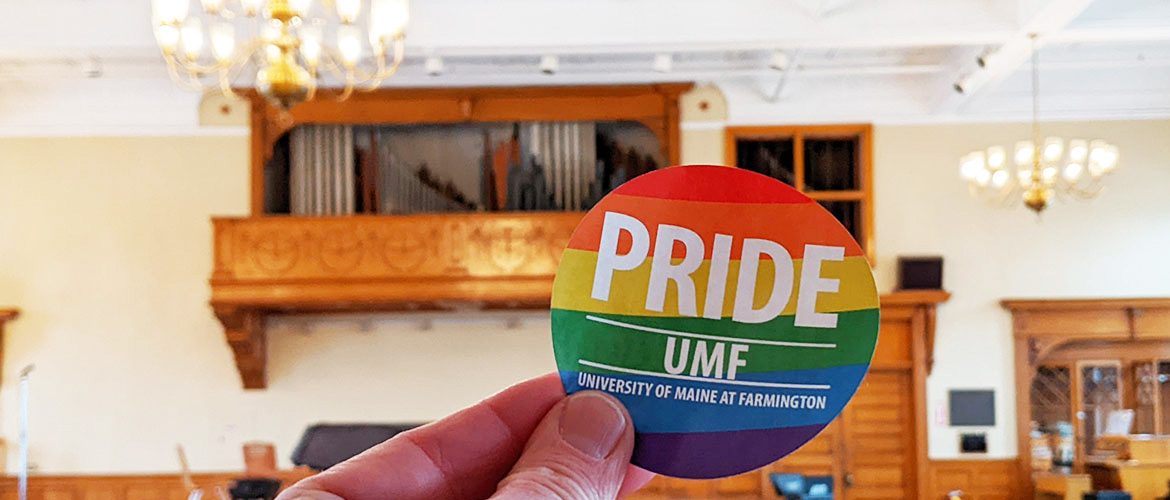 UMF Pride sticker in front of a campus building in the background