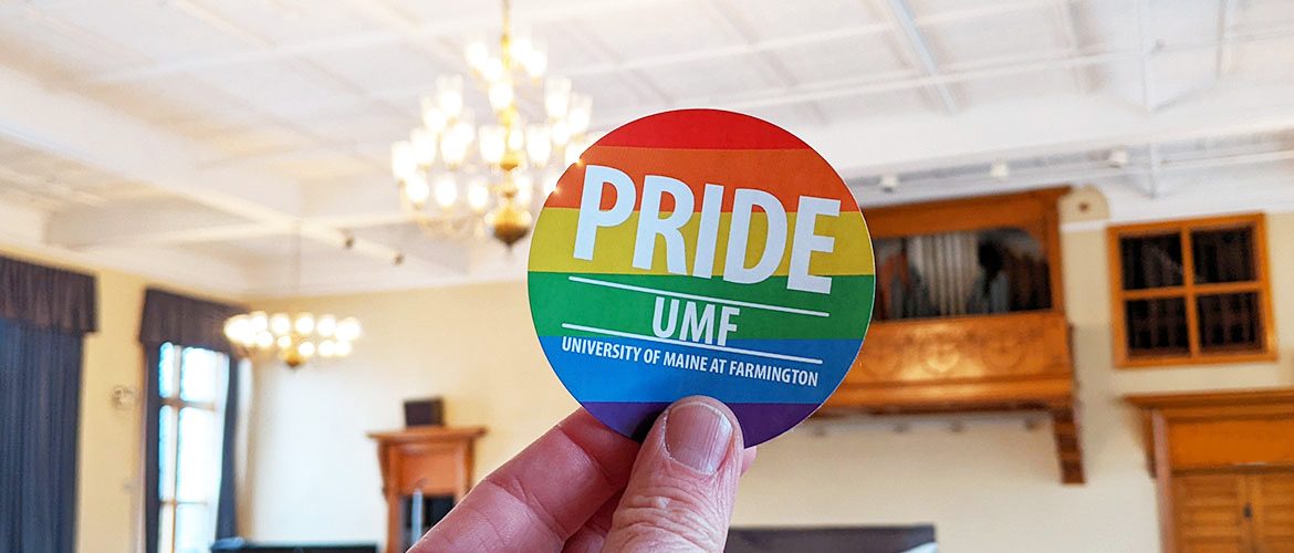 UMF Pride sticker in front of a campus building in the background