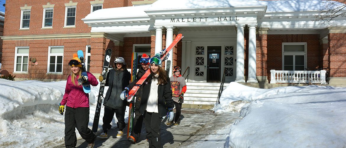 Students leaving residence hall with skis