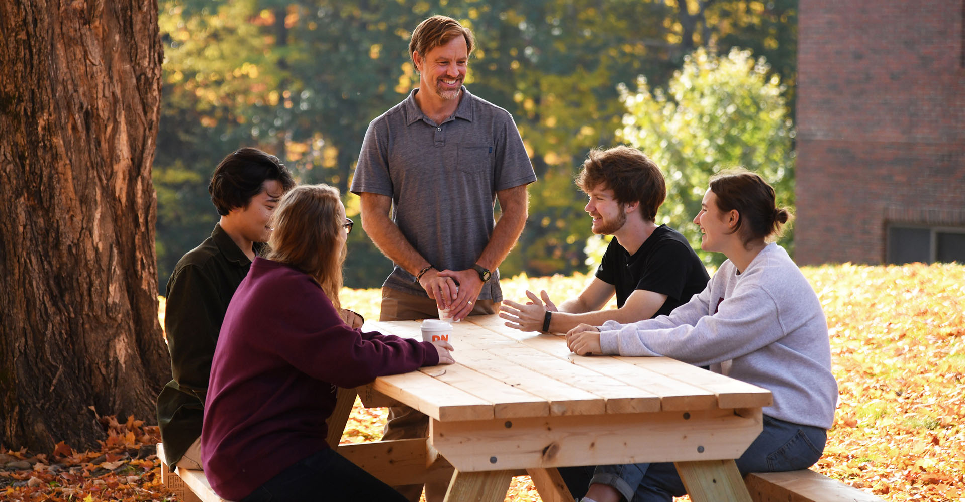 Faculty member with students at an outdoor picnic table
