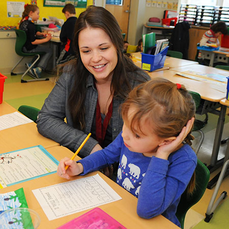 Student teacher working with child in a classroom