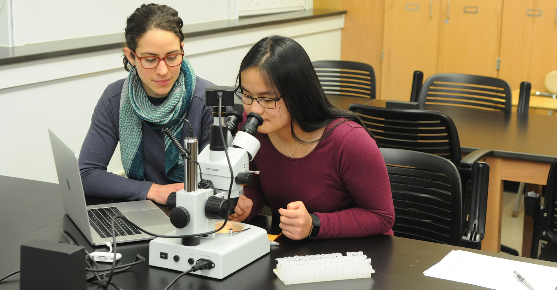 Professor and student using a microscope in a laboratory